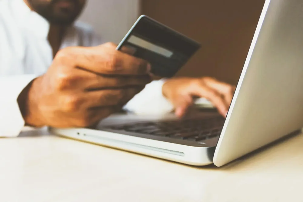 Person typing in their credit card information onto their laptop.