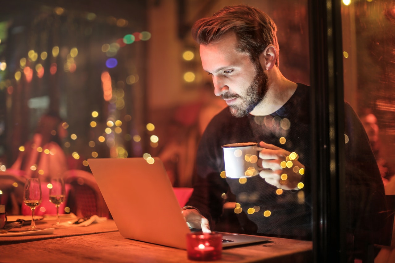 Person sits in a cafe at night on their laptop.