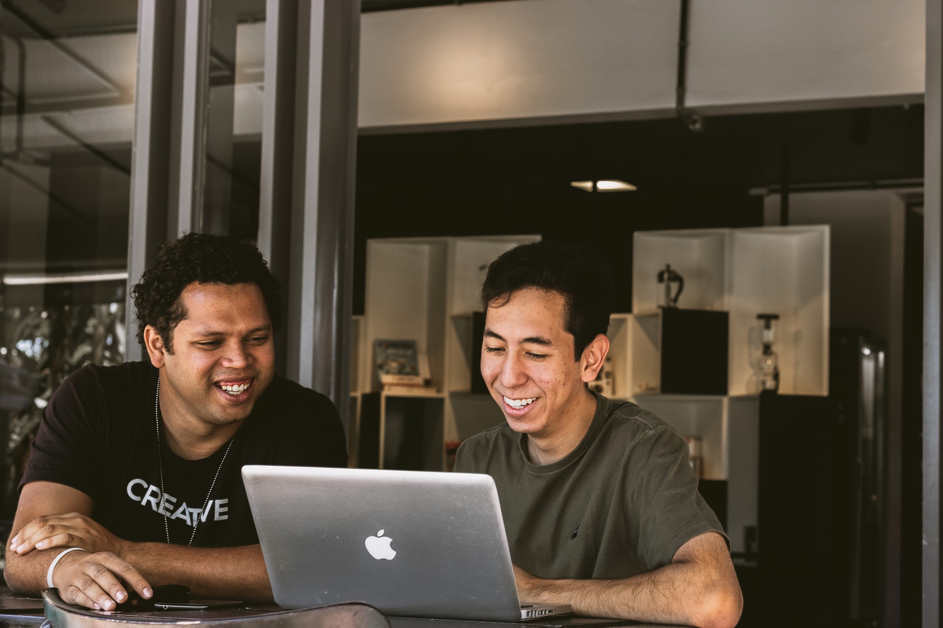 Two people smile down at a laptop screen.