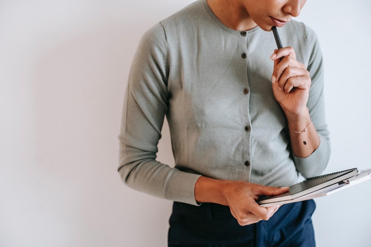 Person holding a notebook and pen ideating.