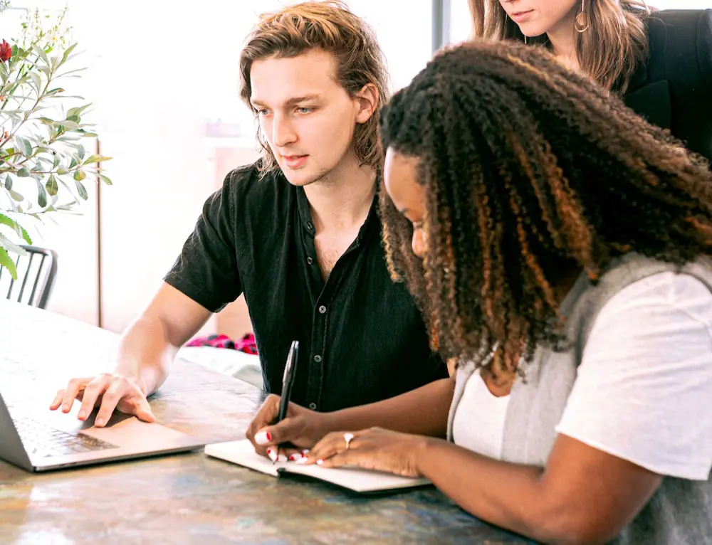 Three people ideate together at a desk on a web design.