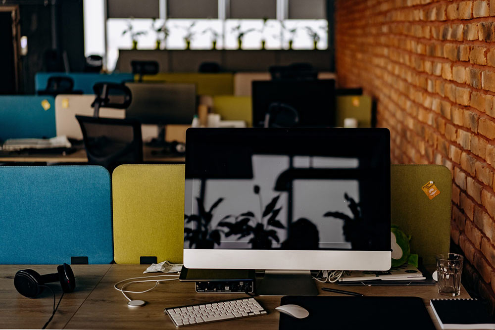 An empty office with desktop screens on every desk.