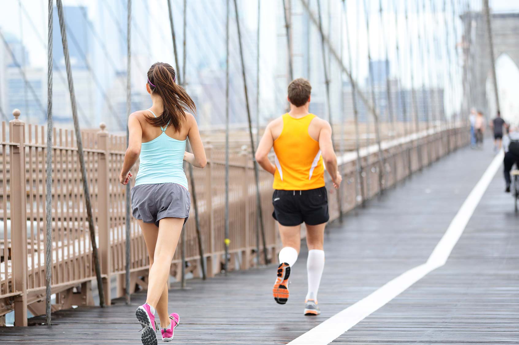 Two people running over bridge.