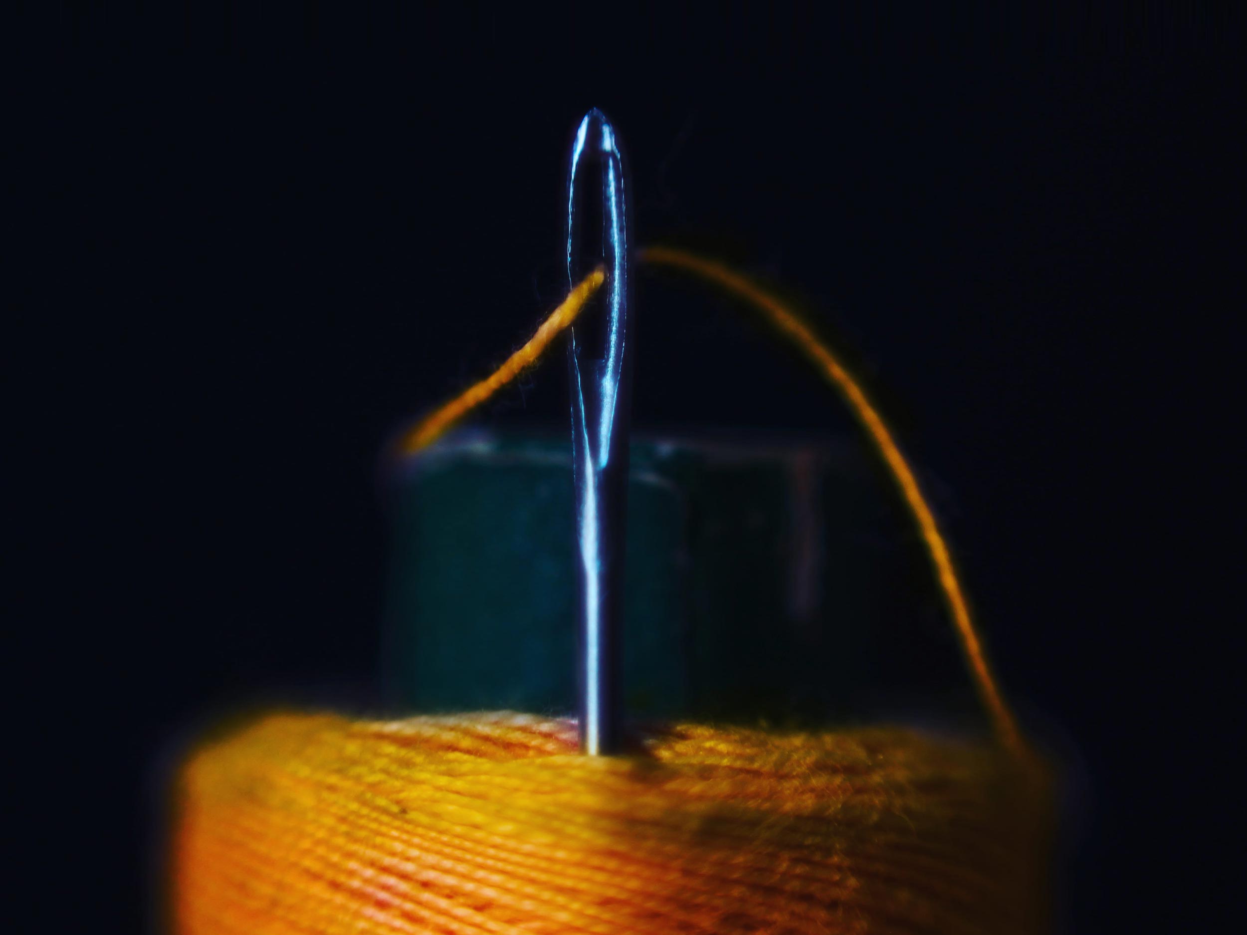 A close up of a piece of yarn going through the loop of a needle.