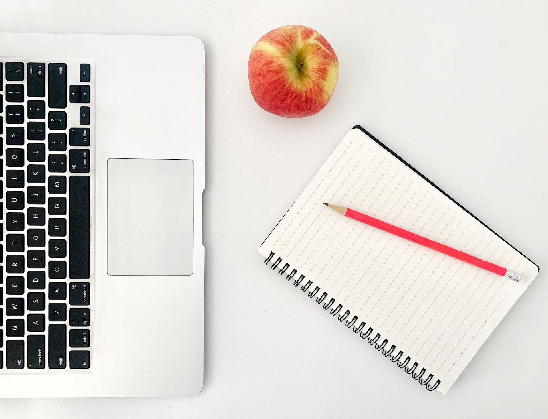 Laptop with notebook and apple in minimalist setting