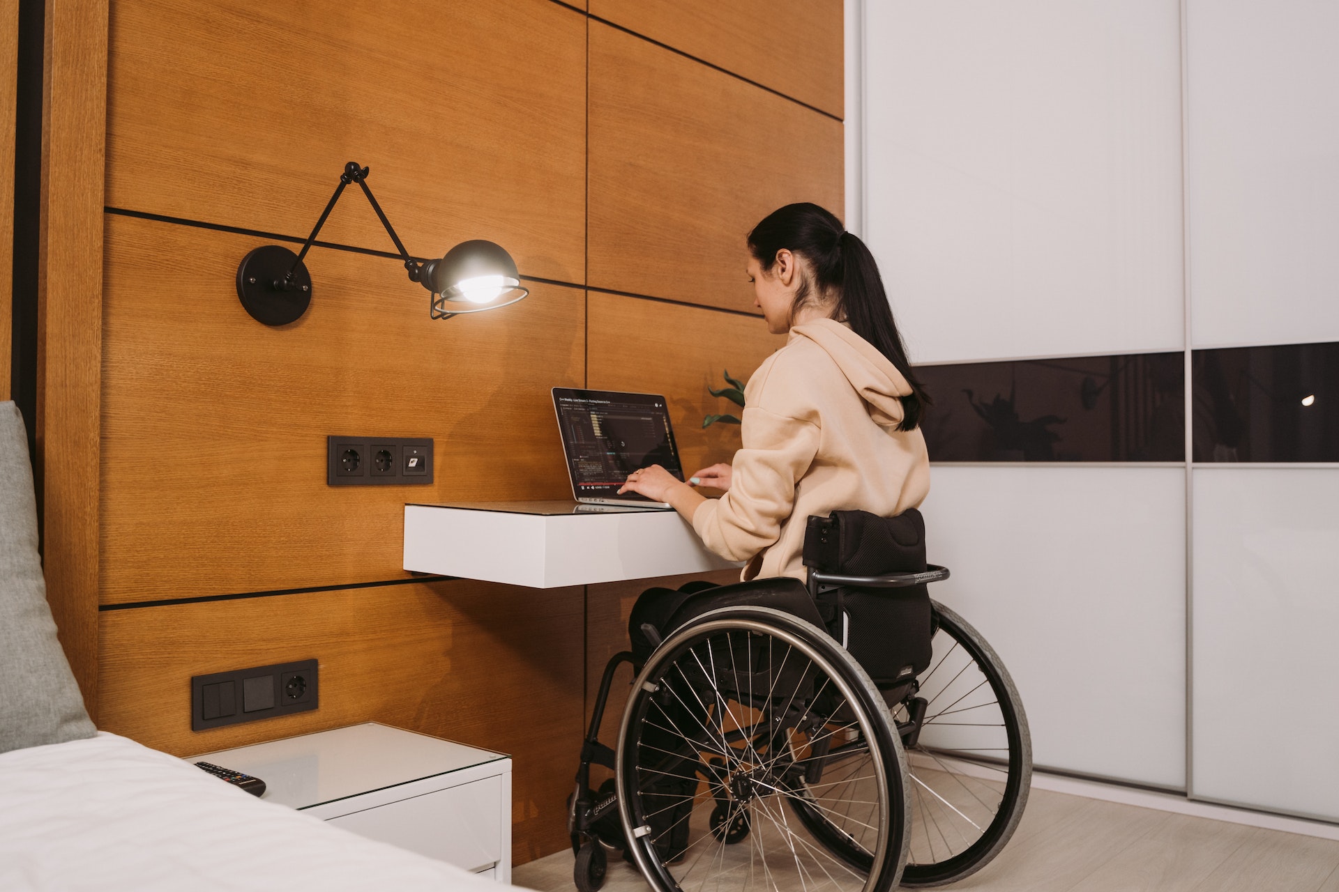person in wheel chair working on a computer at a desk