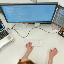An bird eye view of a designer with three desktop screens writing code.