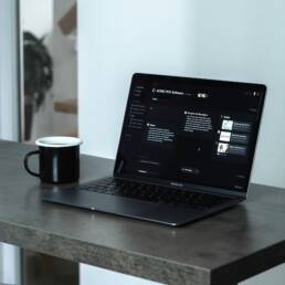 A laptop on a desk next to a coffee mug.