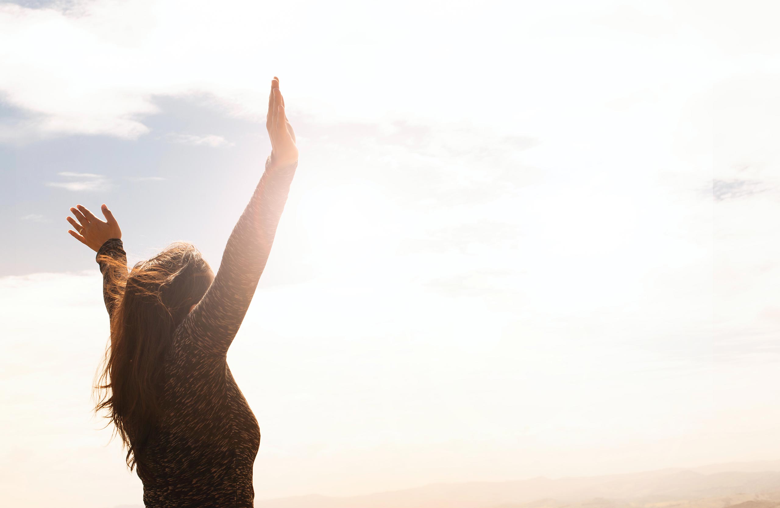 Person holds hands up in joyous pose.