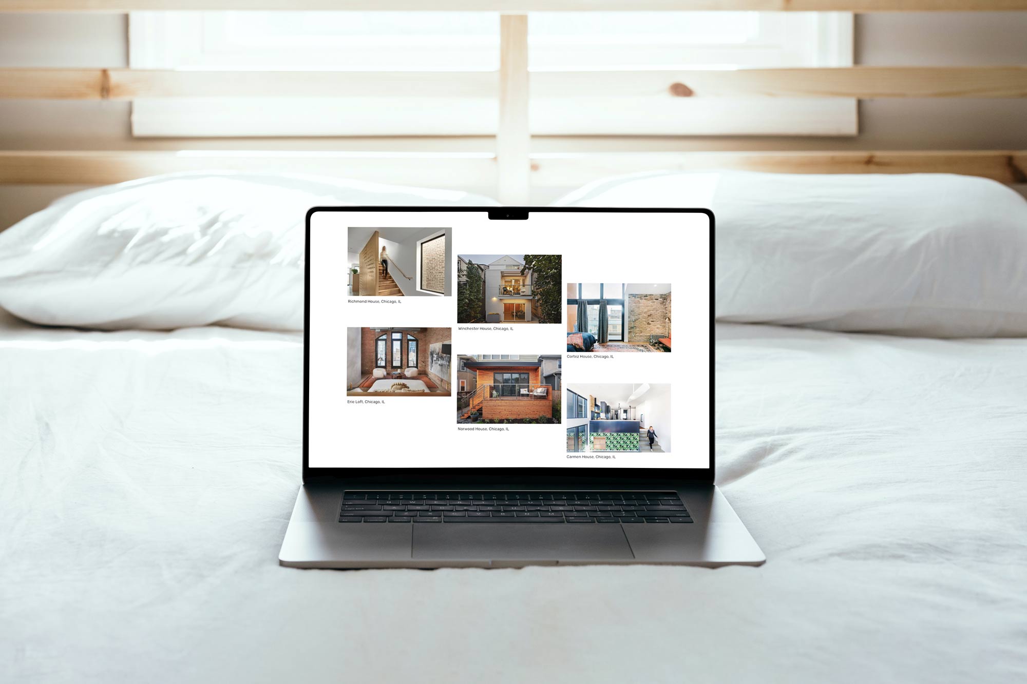 A UX home screen of an architecture website on a laptop sitting on a bed.