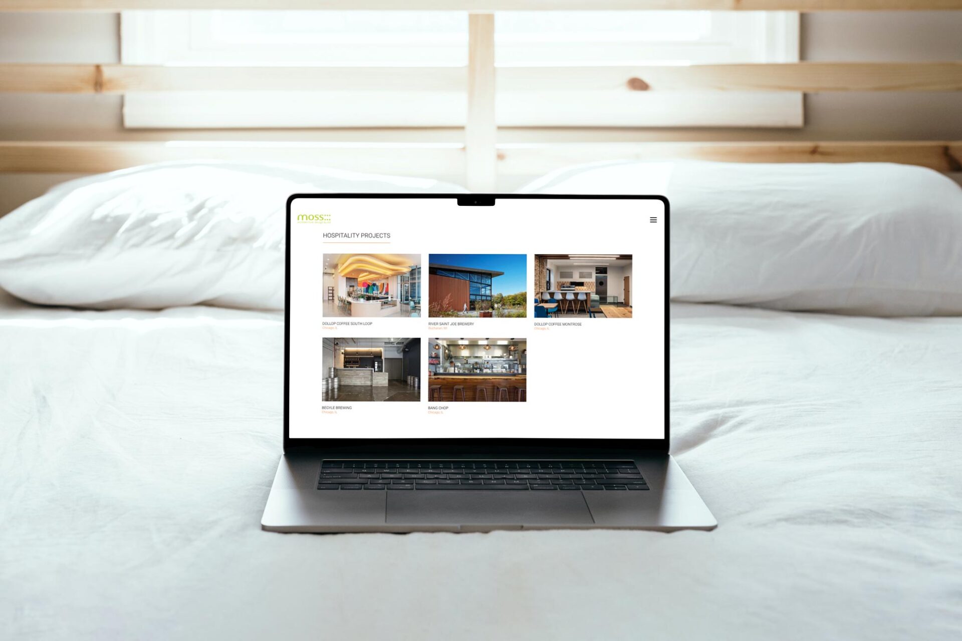 A UX home screen of an architecture website on a laptop sitting on a bed.