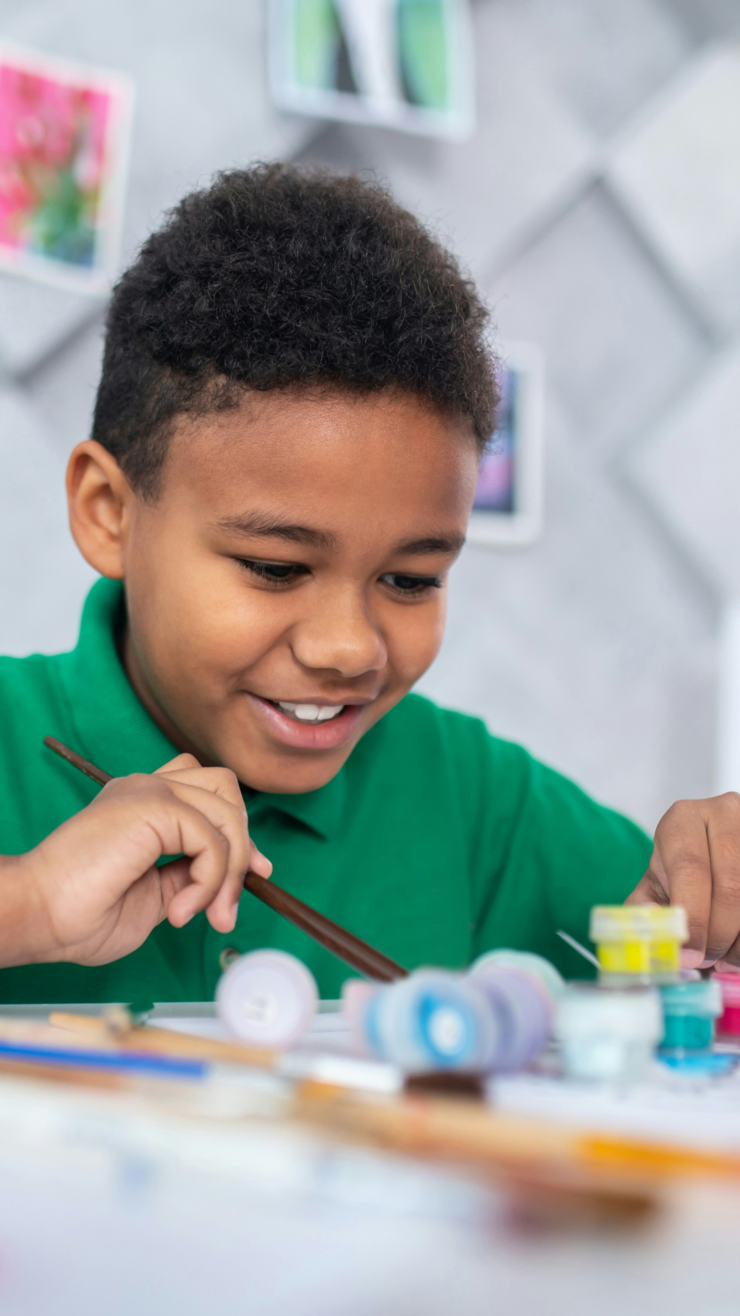 A smiling child draws at a table.