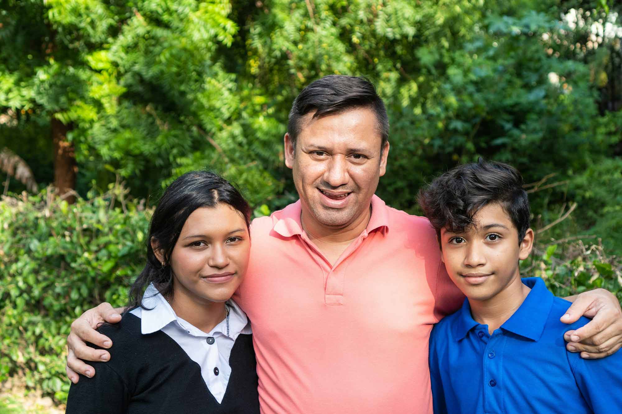 A family smiling with trees behind them.