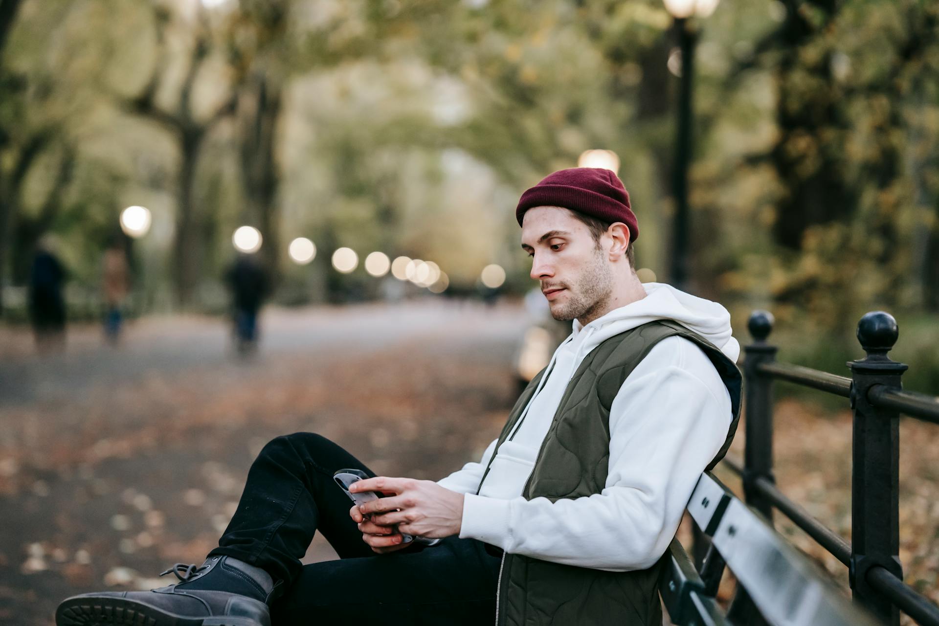 Person sitting on a park bench browsing online on their phone. 