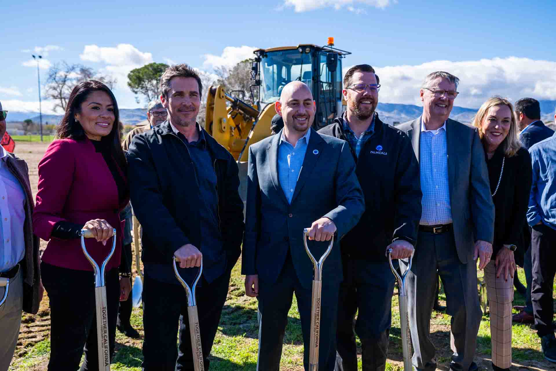 People smile holding shovels.