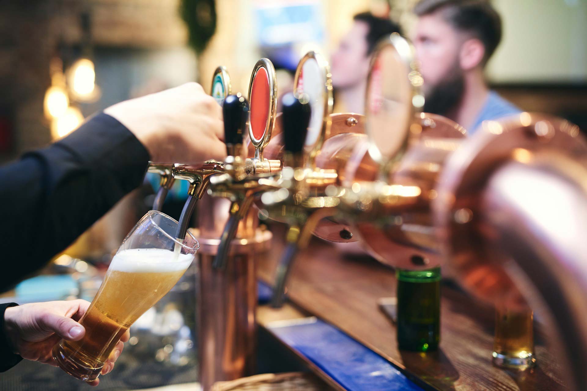 A person pouring a beer from a bar tap.