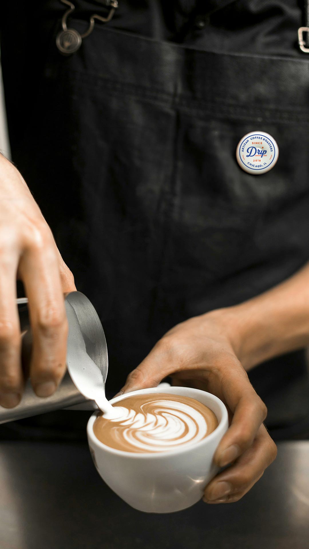 A person pours cream into a cup filled with coffee.