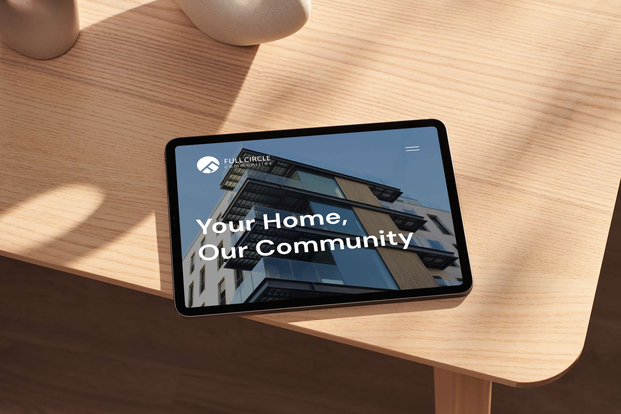 A tablet on a wooden table showcasing a home page design for a real estate website.