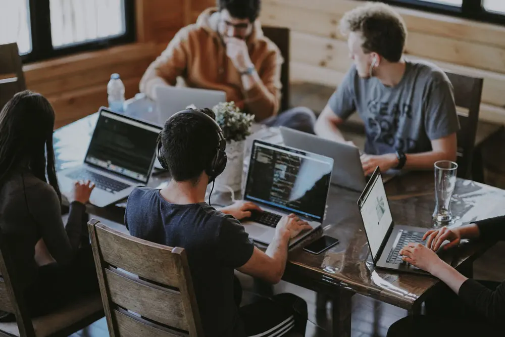 A team of web designers work together on a project on one large table.