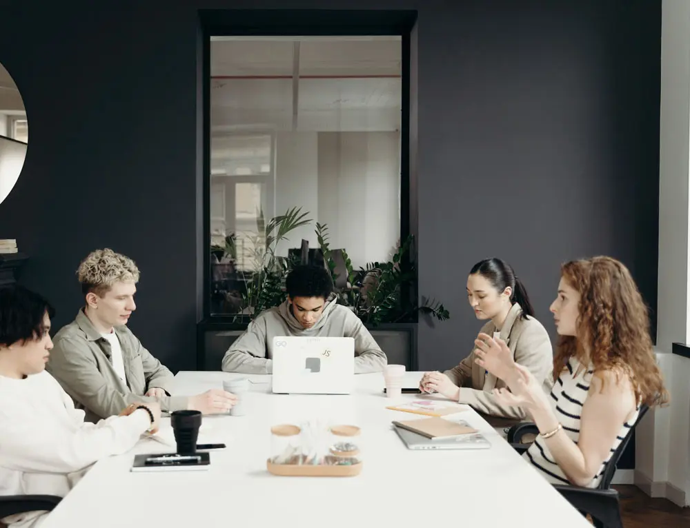 Marketing strategies collaborate with one another while sitting at a desk.