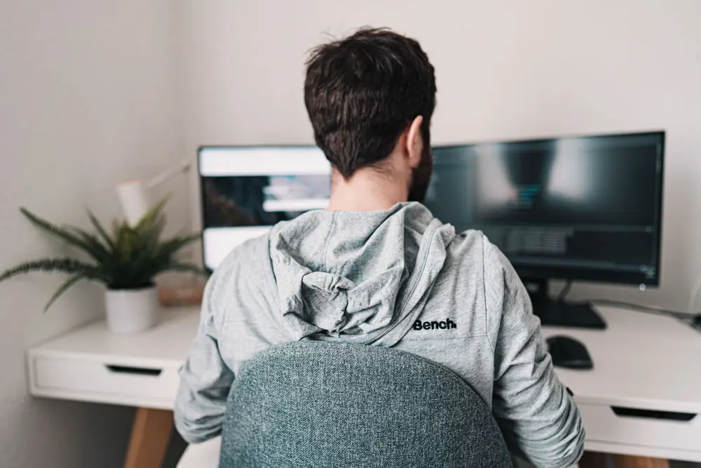 A UX/UI designer works on double monitors.