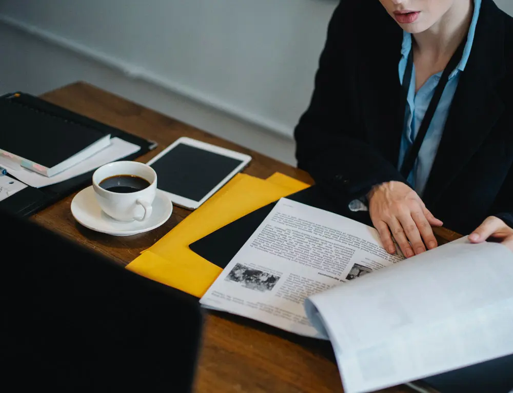 A person looks at design layout while enjoying a cup of coffee.