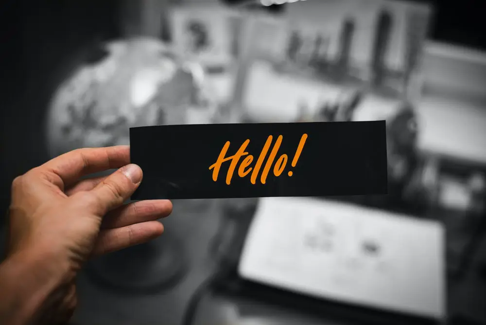 A person holds an object with "Hello" designed on it in orange.