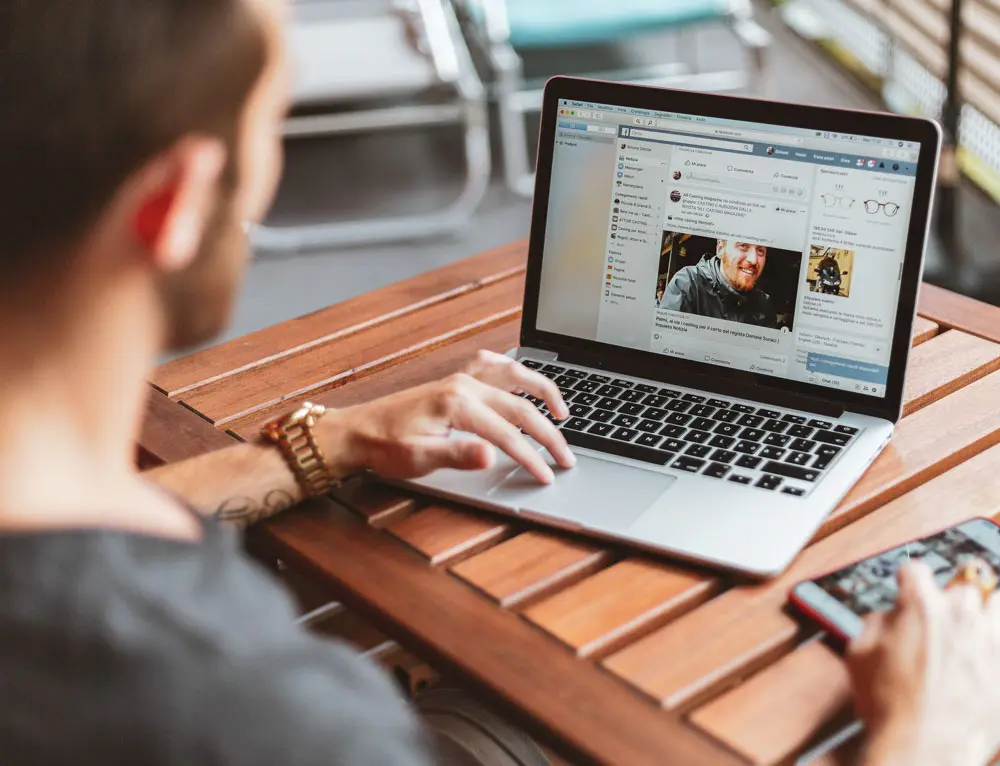 A web designer works from a laptop outdoors.