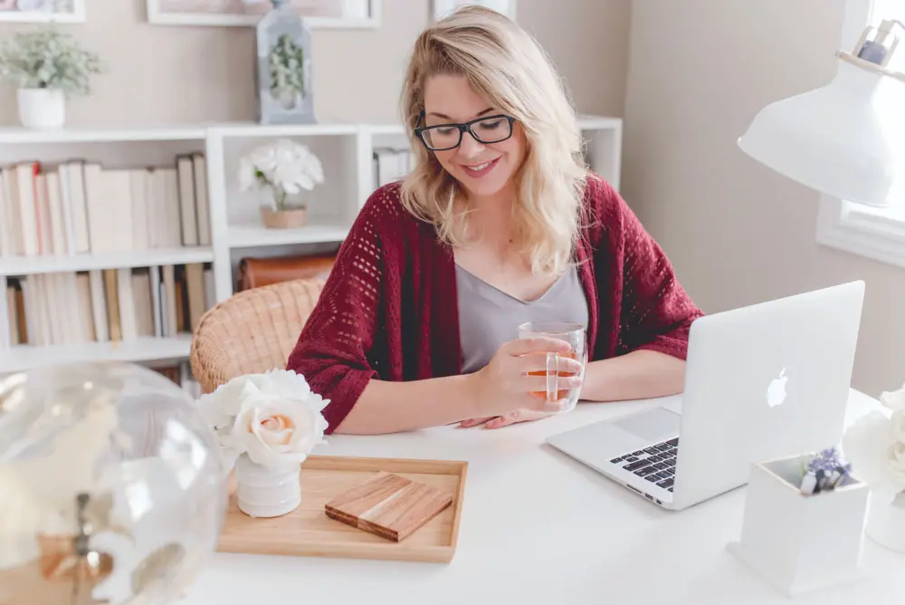 A designer smiles while working on a laptop.