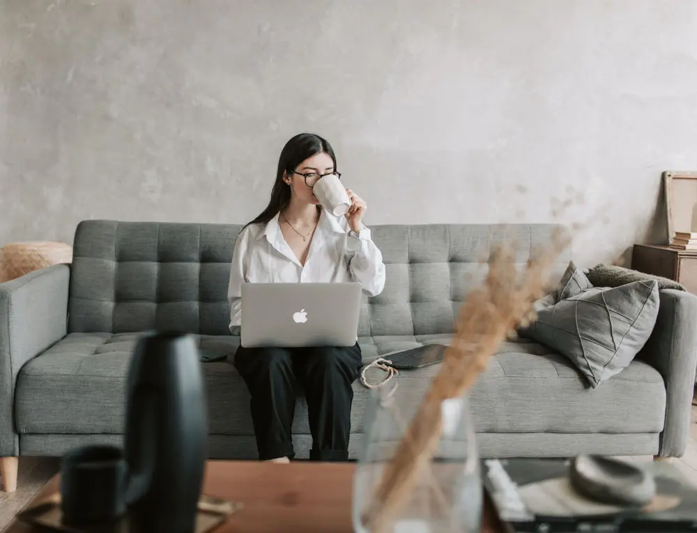 A marketer works on laptop while drinking coffee.