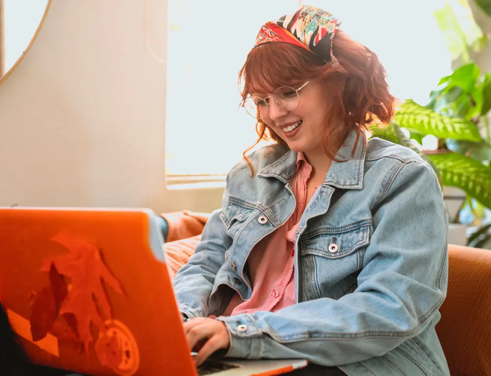 A graphic designer smiles while working on laptop.