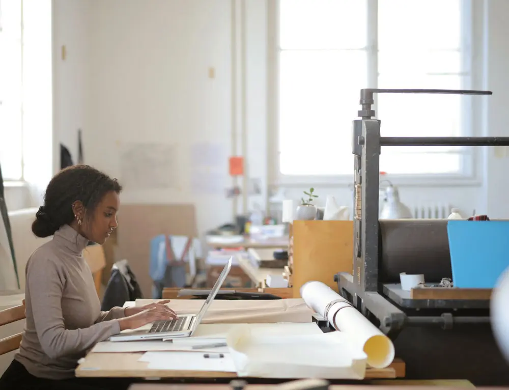 A person designs on a large desk in a studio.