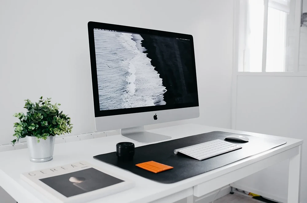 A white, minimalist office with a desktop screen of an ocean screensaver.