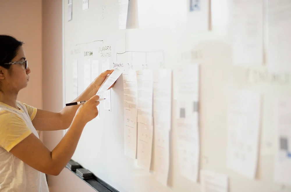 A designer strategizing user pathways on a white board.