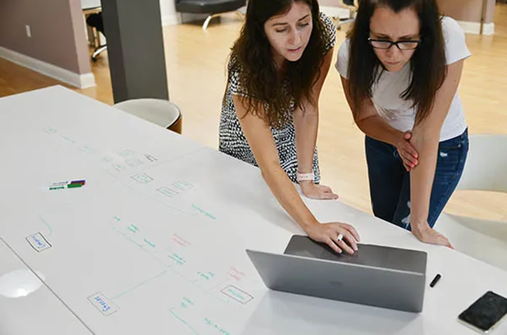 Designers sketching and looking at a laptop screen.