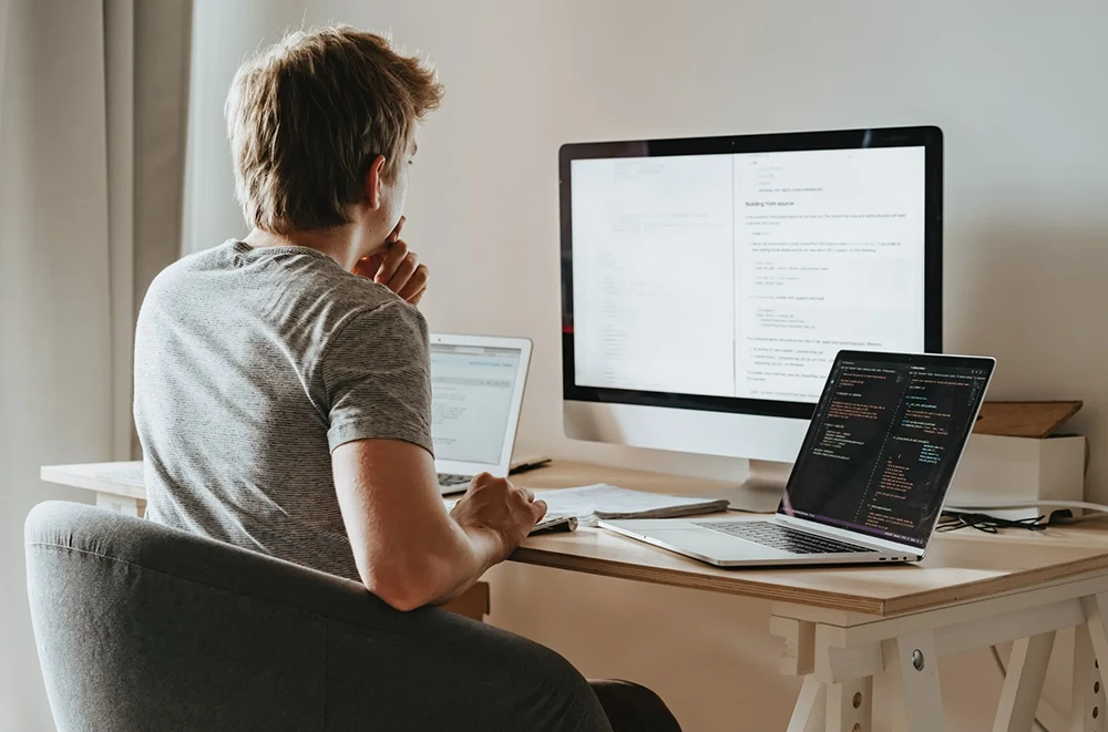 A developer using multiple devices to develop website.