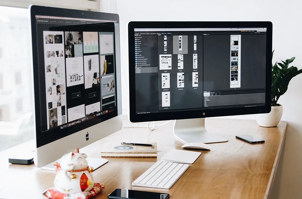 Two desktop monitors displaying web design process.