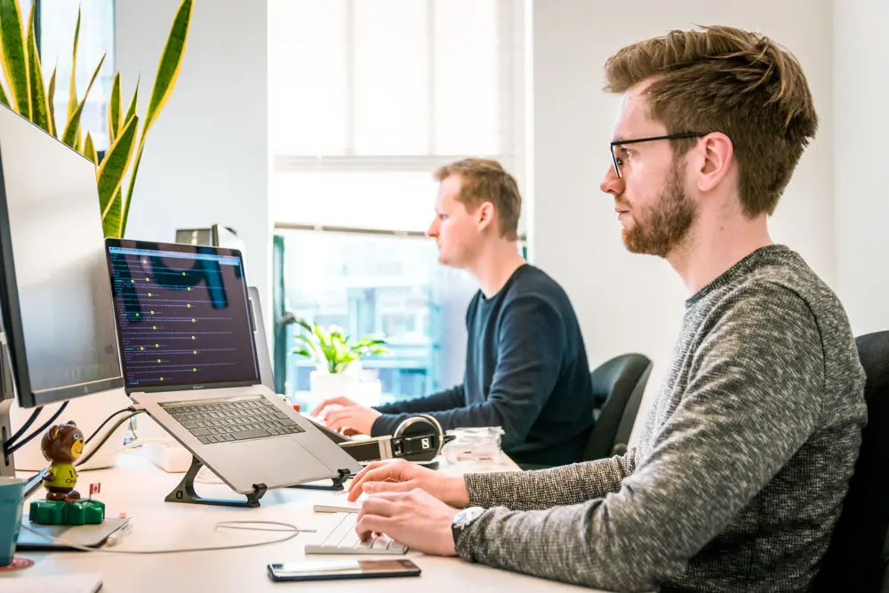 Web designers work while sitting by each other.