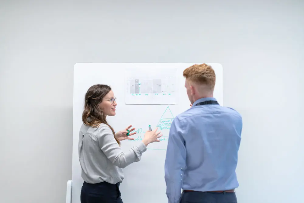 Two designers ideate at a white board.
